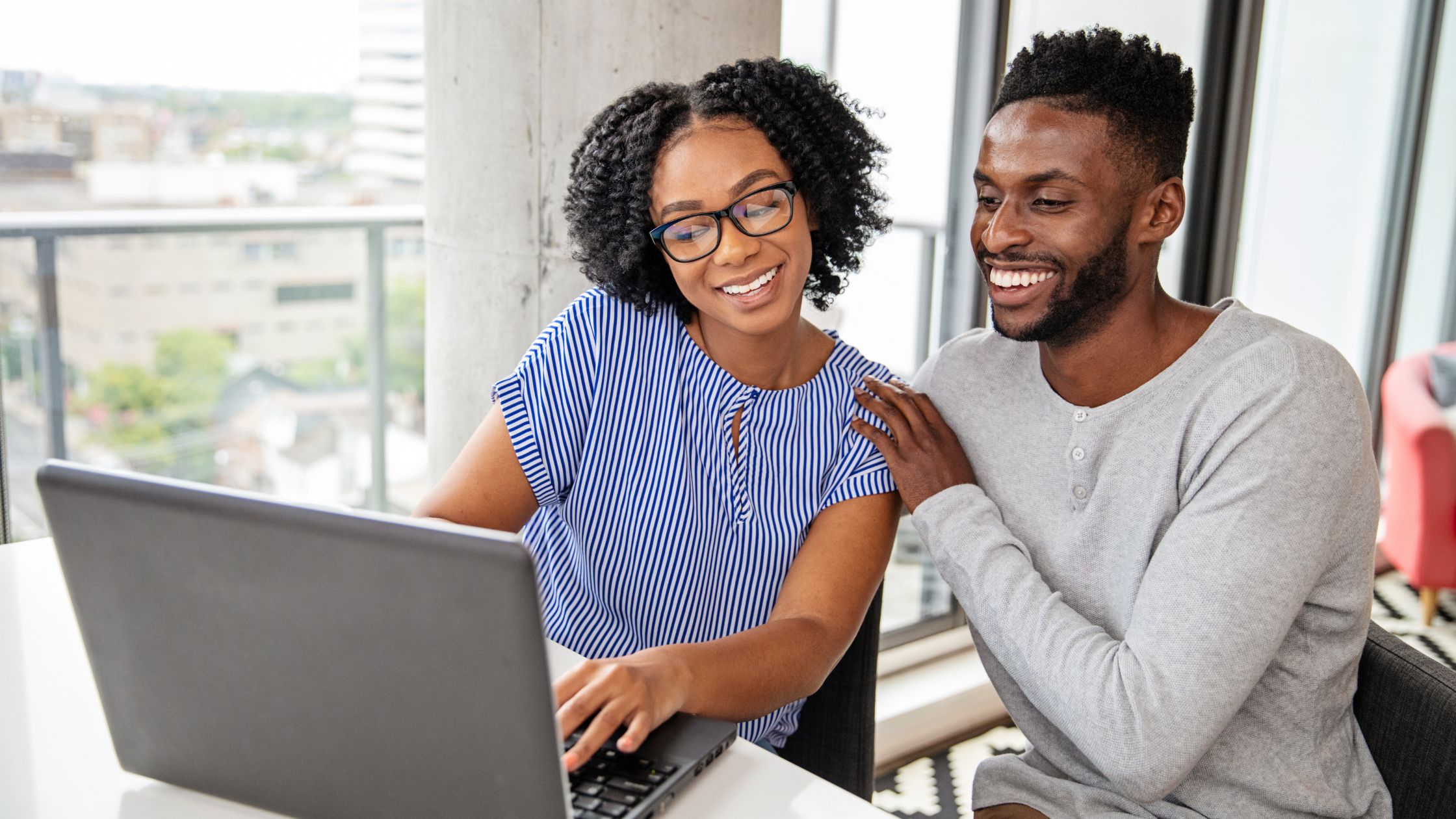 black couple smiling looking at computer