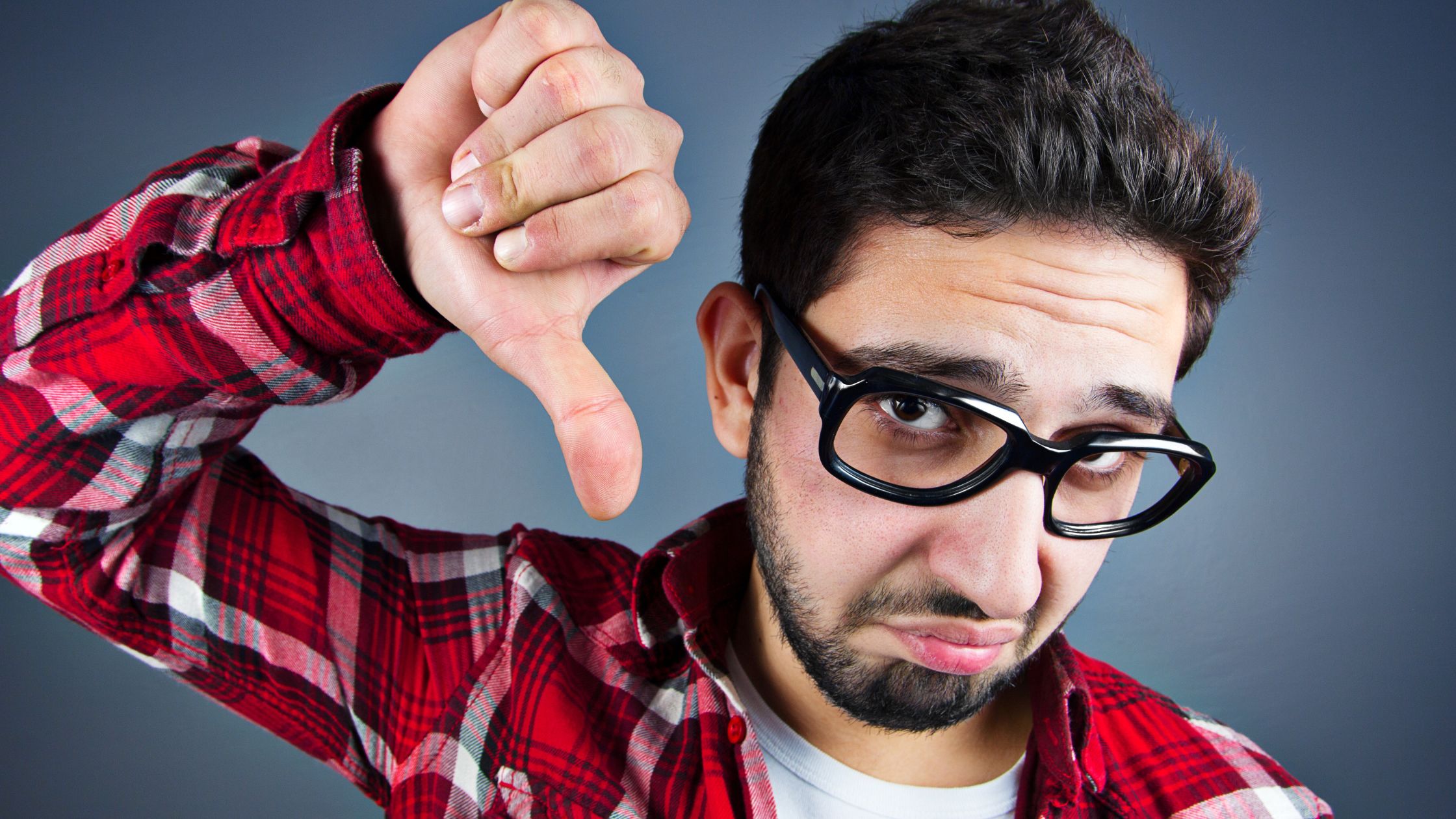 man wearing glasses with thumb pointed down